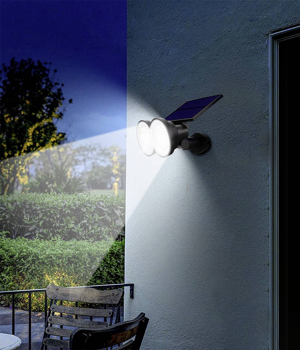 Zonne-energiebuitenlamp met dubbele stralers die een tuingedeelte verlichten in het donker.