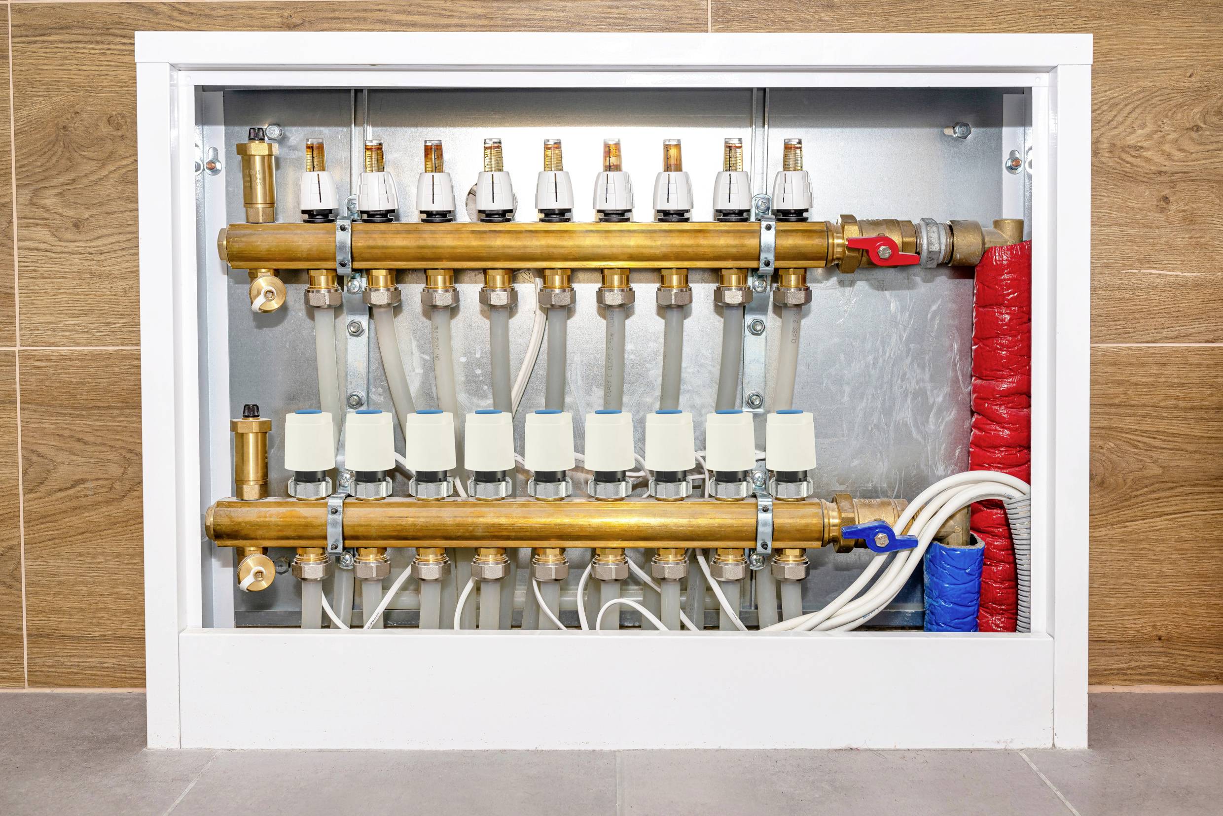 Een verdeler met meerdere buizen en kleppen voor vloerverwarming. Buizen zijn aangesloten voor het regelen van de verwarmingscircuits.