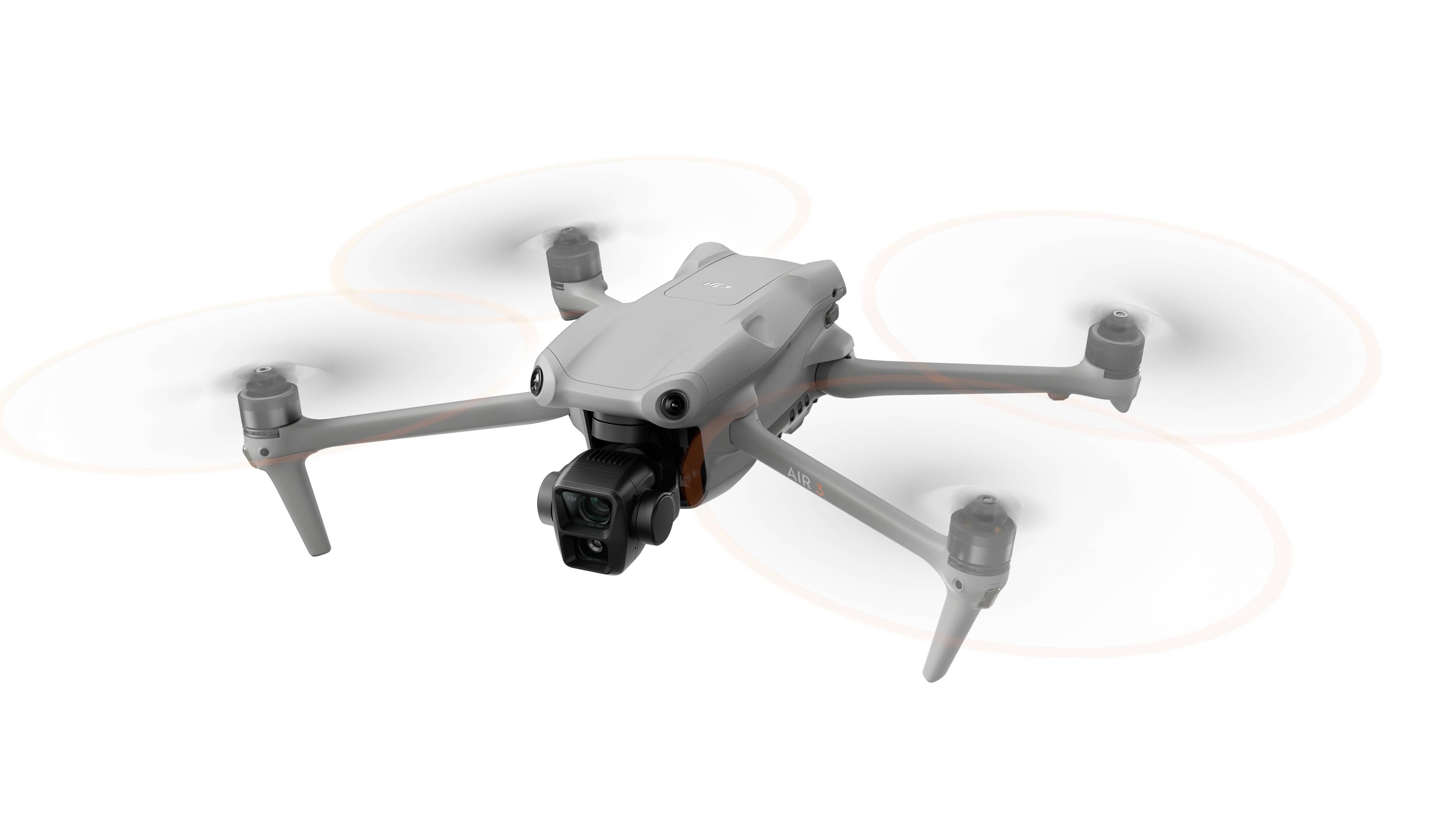 Een witte drone met vier propellers vliegt. Hij heeft een camera aan de voorkant en is in beweging.