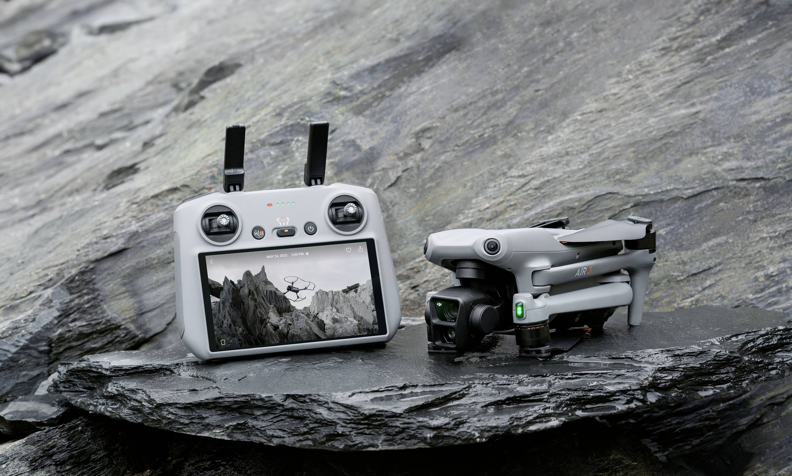 Een drone en een afstandsbediening liggen op een rots. Op het scherm van de afstandsbediening is een berglandschap te zien.