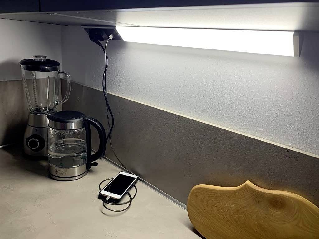 'Keuken met mixers, waterkoker en smartphone op het aanrecht. Heldere lamp boven het hoofd verlicht de scène.'