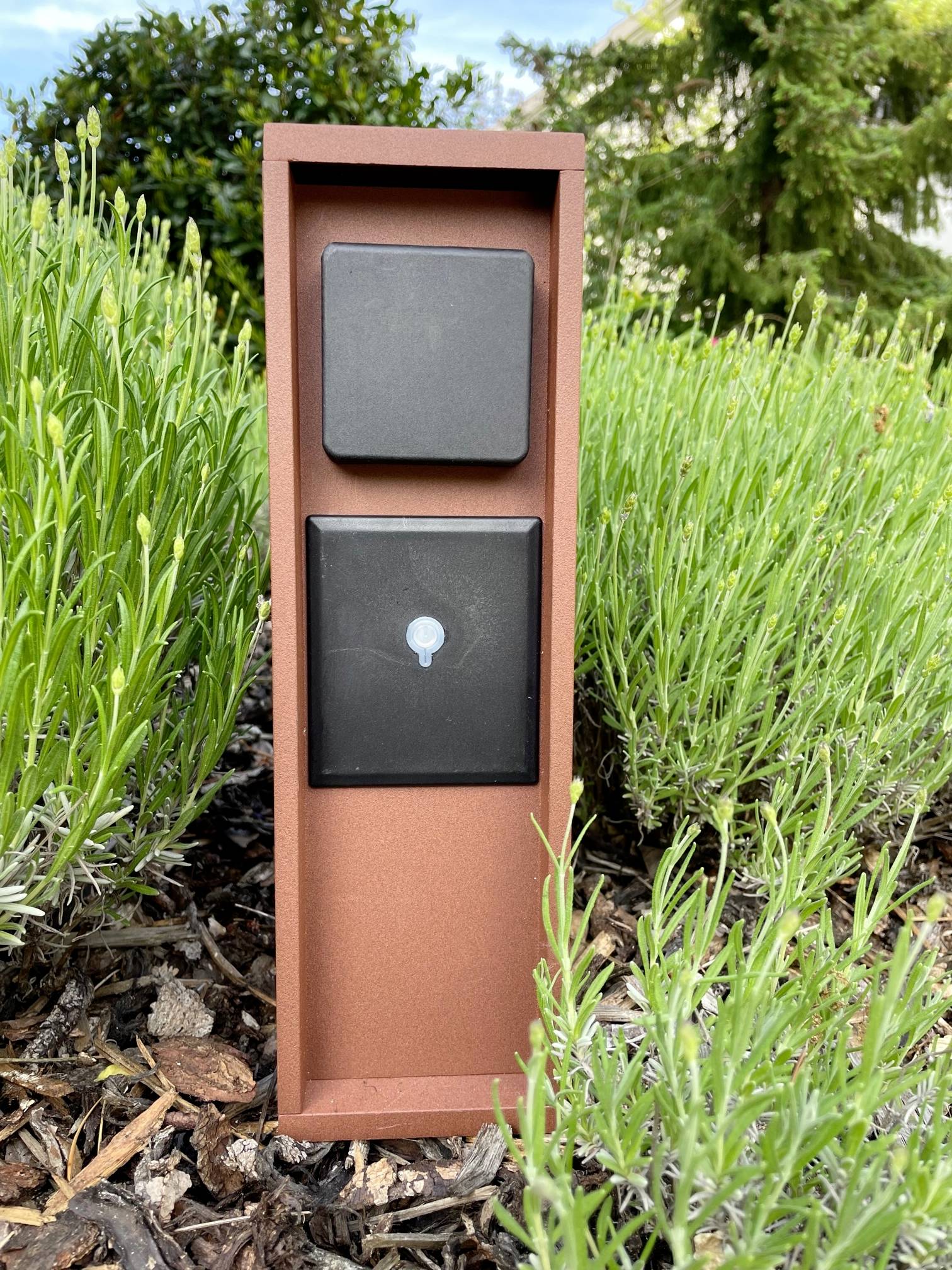 Een roodbruine behuizingsstandaard in de tuin met zwarte vierkante elementen, omgeven door groene planten en aarde.
