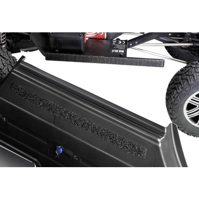 Afstandsbediend voertuig, met focus op het zwarte kunststof chassis met textuurdetail en wielgedeelte. Bovenste deel van de voertuigmechanica zichtbaar.