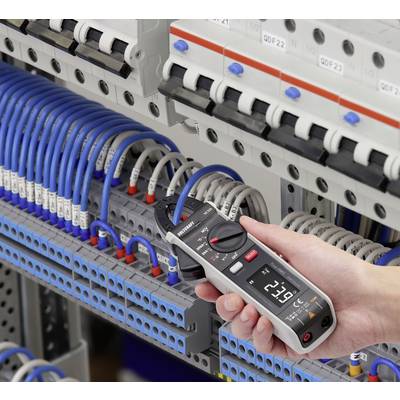 Een persoon meet de spanning in een schakelkast met een digitaal multimeter. Kabels zijn aangesloten op verschillende aansluitpunten.