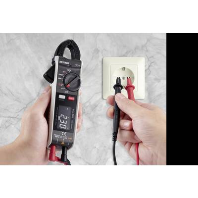 Twee handen testen een stopcontact met een digitaal multimeter en meetkabels. Het display toont '0.22', wisselstroommetingen.