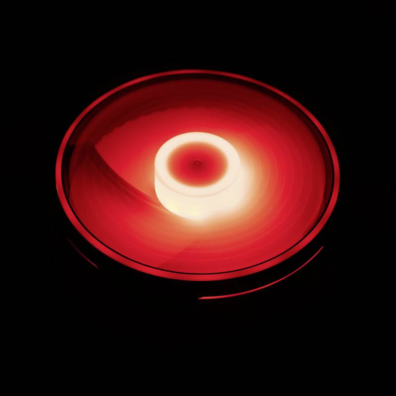 Een rood verlicht, cirkelvormig voorwerp op een zwarte achtergrond dat een hypnotische, spiraalvormige lichtwerking genereert.