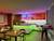 Een moderne ruimte met een verlichte bar in levendige kleuren. Houten tafel en stoelen bevinden zich op de voorgrond. Sfeervol en uitnodigend.