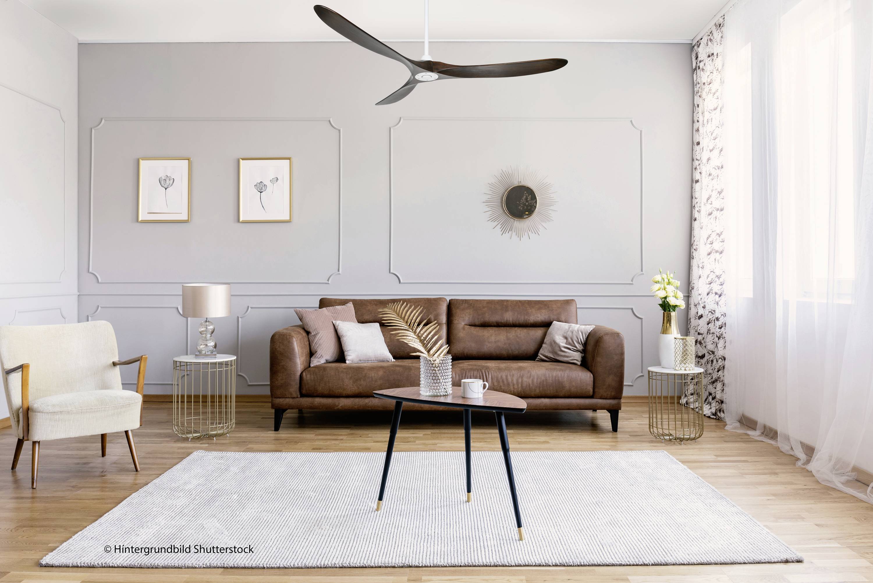 Een modern ingericht woonkamer met een bruin leren bank, beige fauteuils, een ronde salontafel, een lichtgrijze vloerkleed en elegante decoratie.