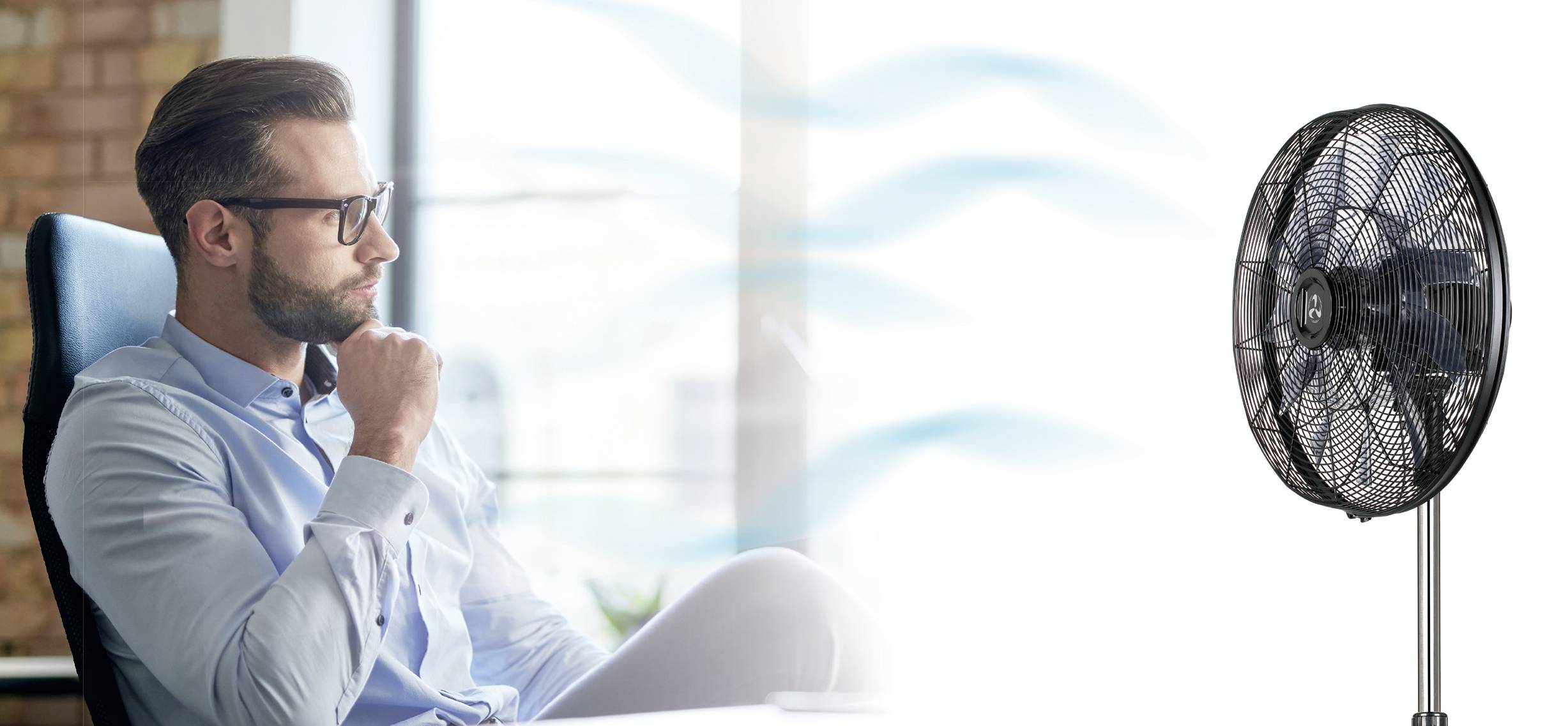 Een man zit nadenkend aan een bureau en kijkt naar een ventilator waaruit luchtstromingen waaien.