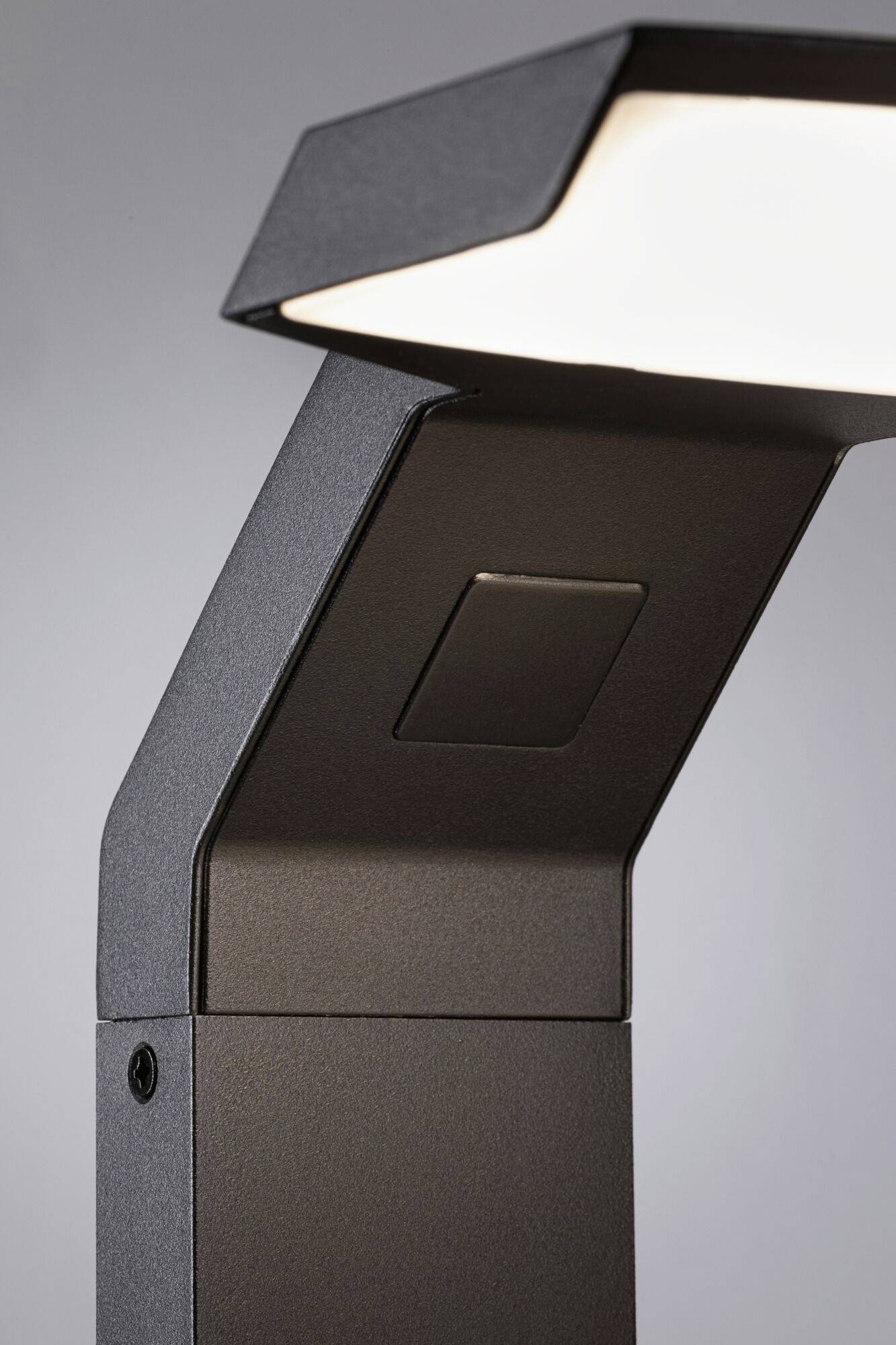 Een moderne zwarte buitenlamp straalt uit met diffuus licht. De geometrische, hoekige stijl geeft een eigentijdse uitstraling.