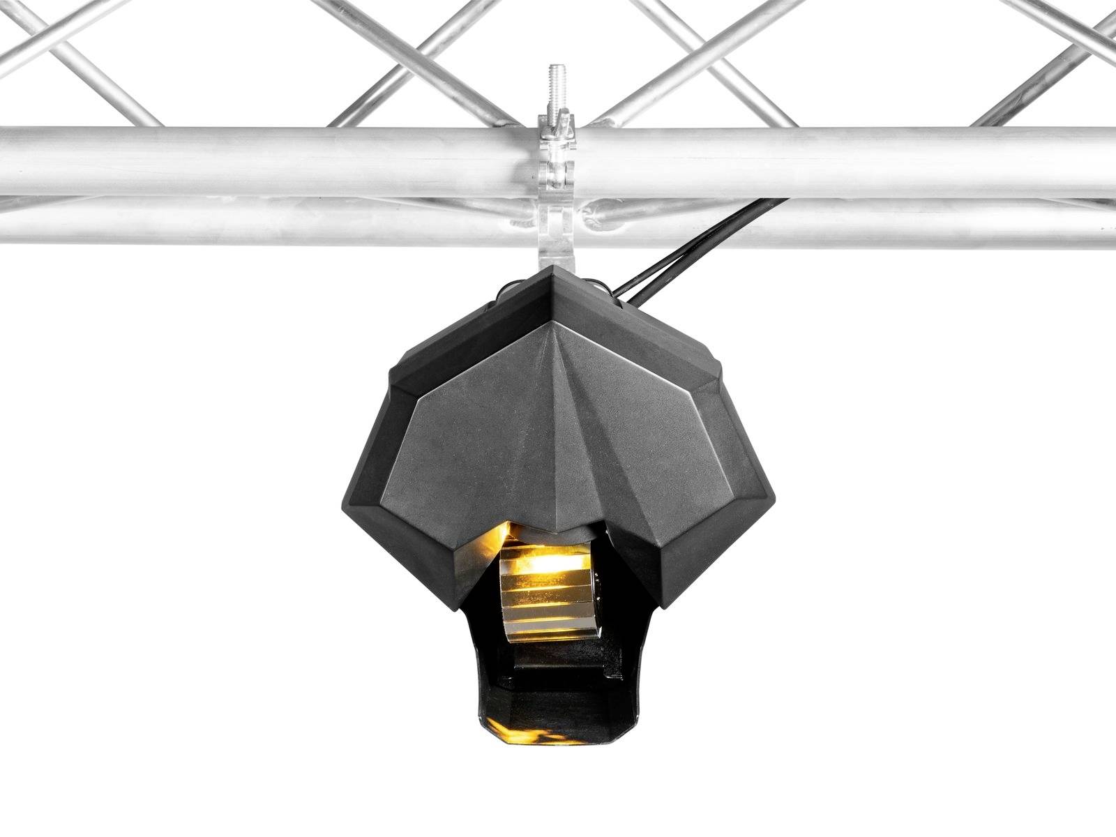 Zwarte sensor met geel licht, gemonteerd op een zilverkleurig metalen rooster, voor bewegingsdetectie in een industriële omgeving.