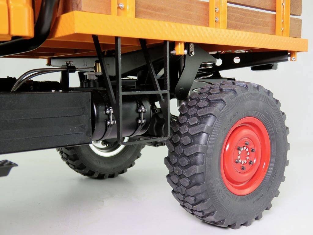 Deel van een voertuig met grote, grove banden en een robuust chassis. Houtlading is zichtbaar op de laadruimte.