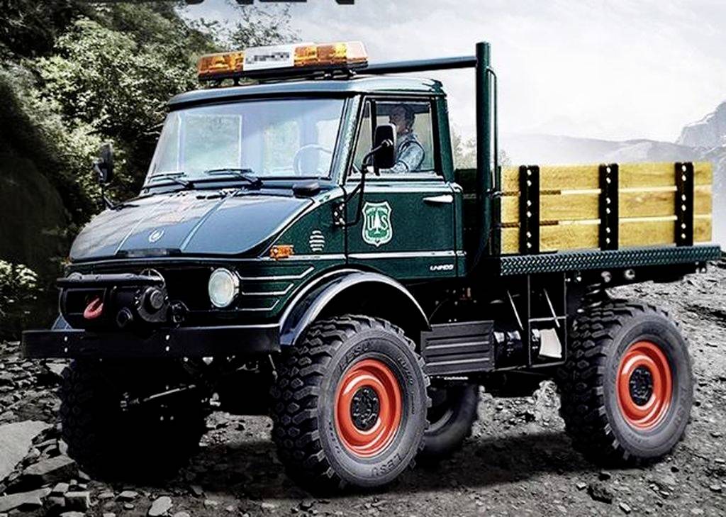 Een groene vrachtwagen met het logo van de US Forest Service rijdt over een rotsachtig pad door een bebost landschap.