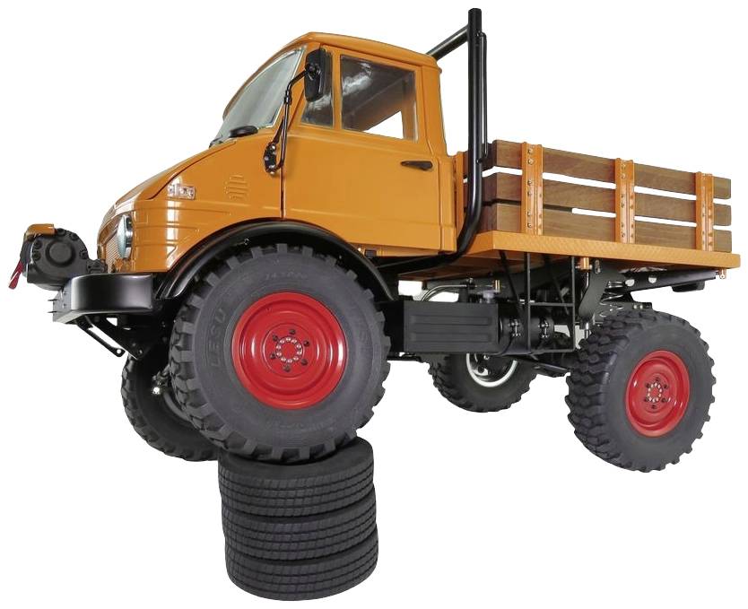 Een oranje Unimog staat schuin op een stapel autobanden, met de wielen in de lucht, wat zijn terreinvaardigheid demonstreert.
