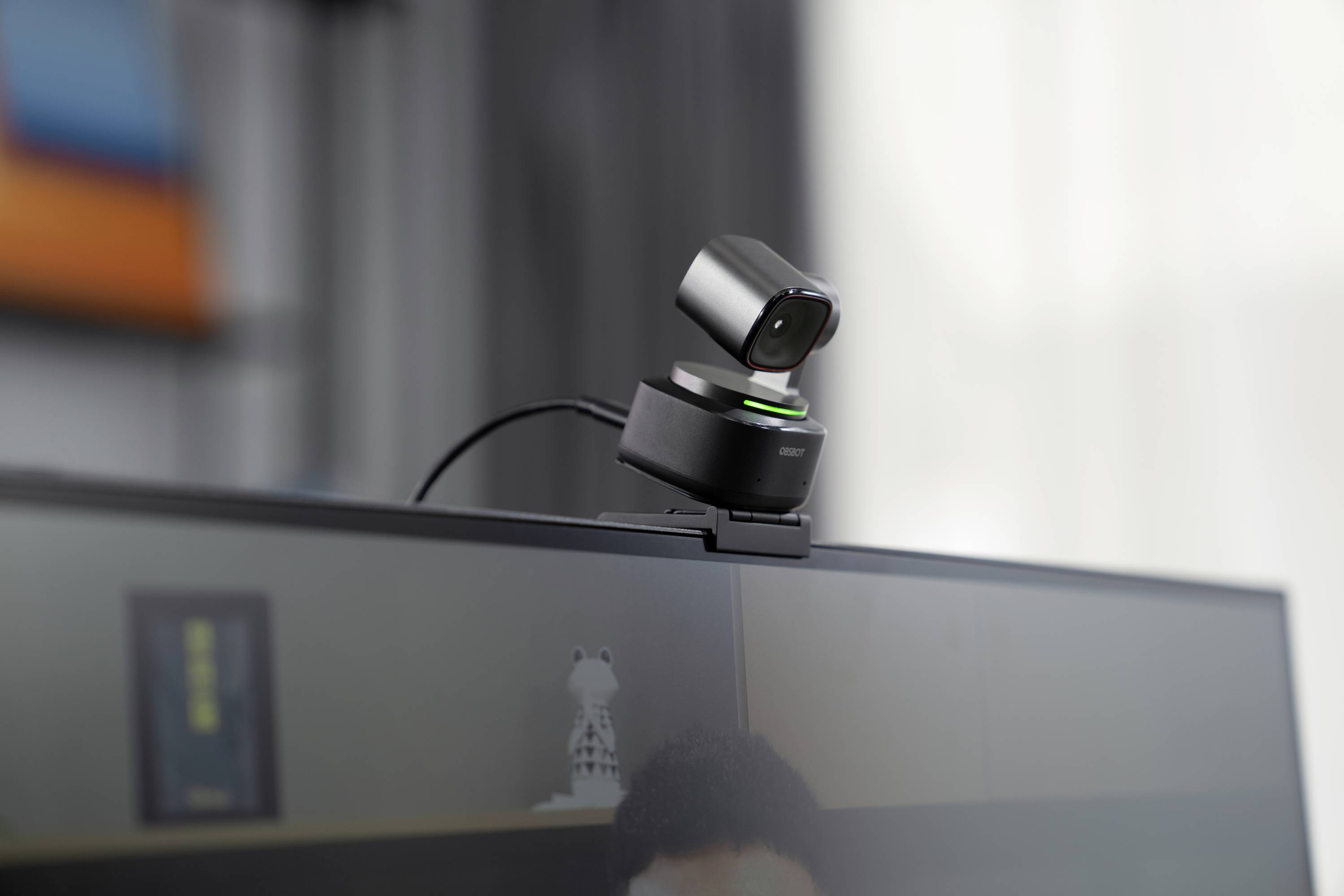 Een webcam is gemonteerd op een monitor en wijst licht naar beneden. Op de achtergrond is een wazig vertrek te zien.