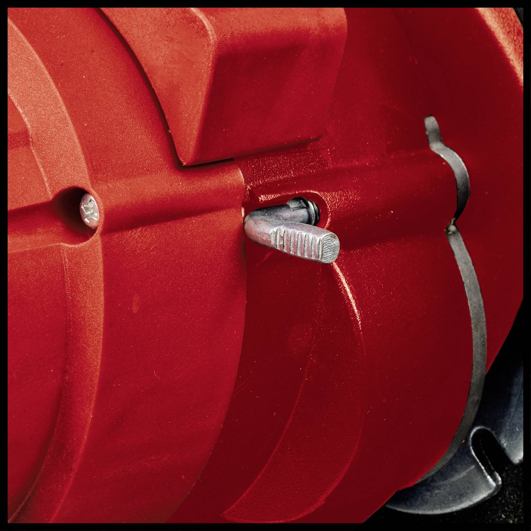 Close-up van een rood machinedeel met een zilveren schroef en hefboom. Overheersende rood- en metaaltinten.