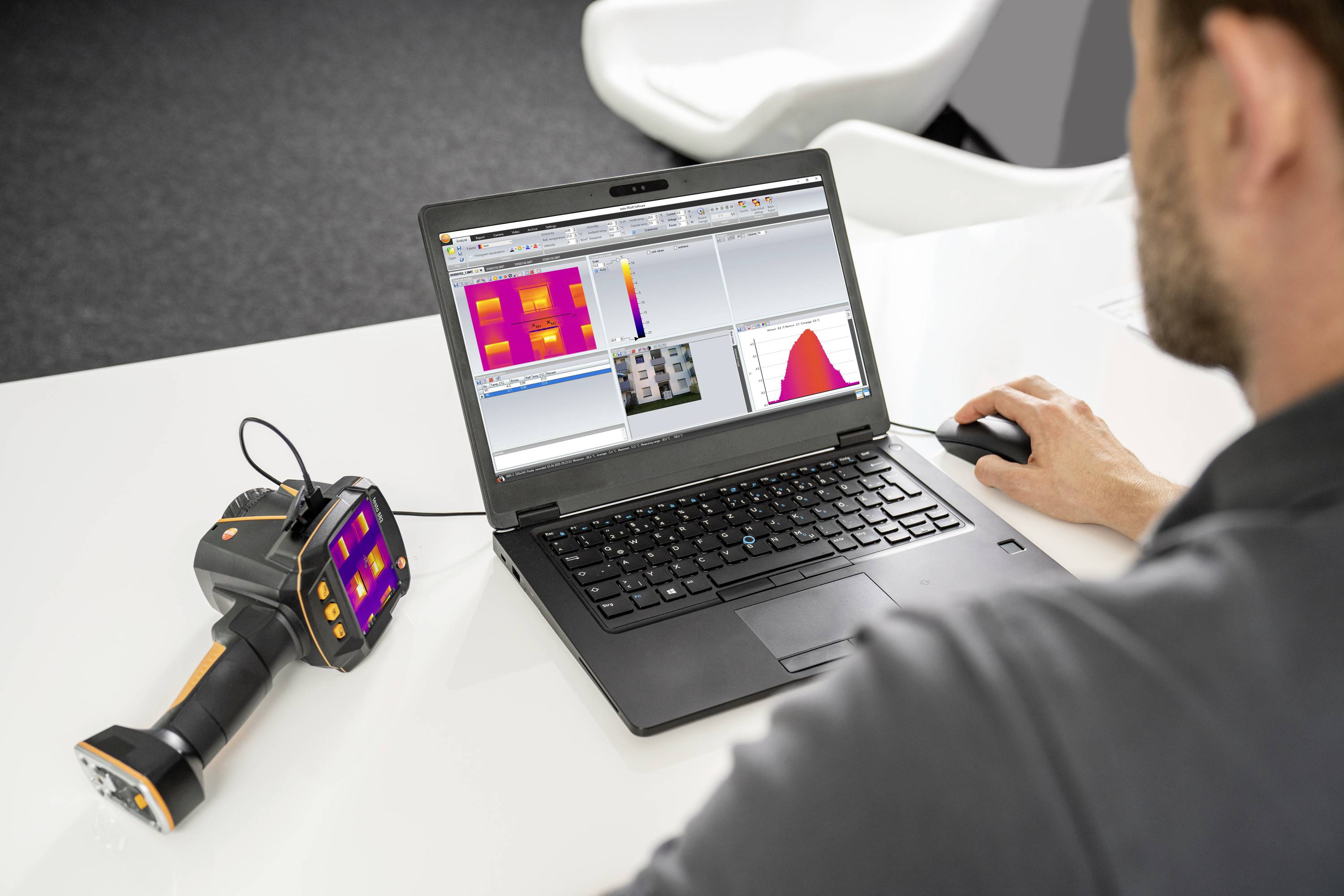 Een man analyseert warmtebeelden op een laptop. Naast hem op tafel ligt een handapparaat, vermoedelijk een thermografische camera.