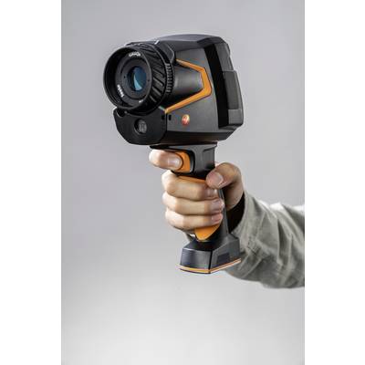 Een hand houdt een infraroodcamera vast, gericht op een grijze achtergrond.
