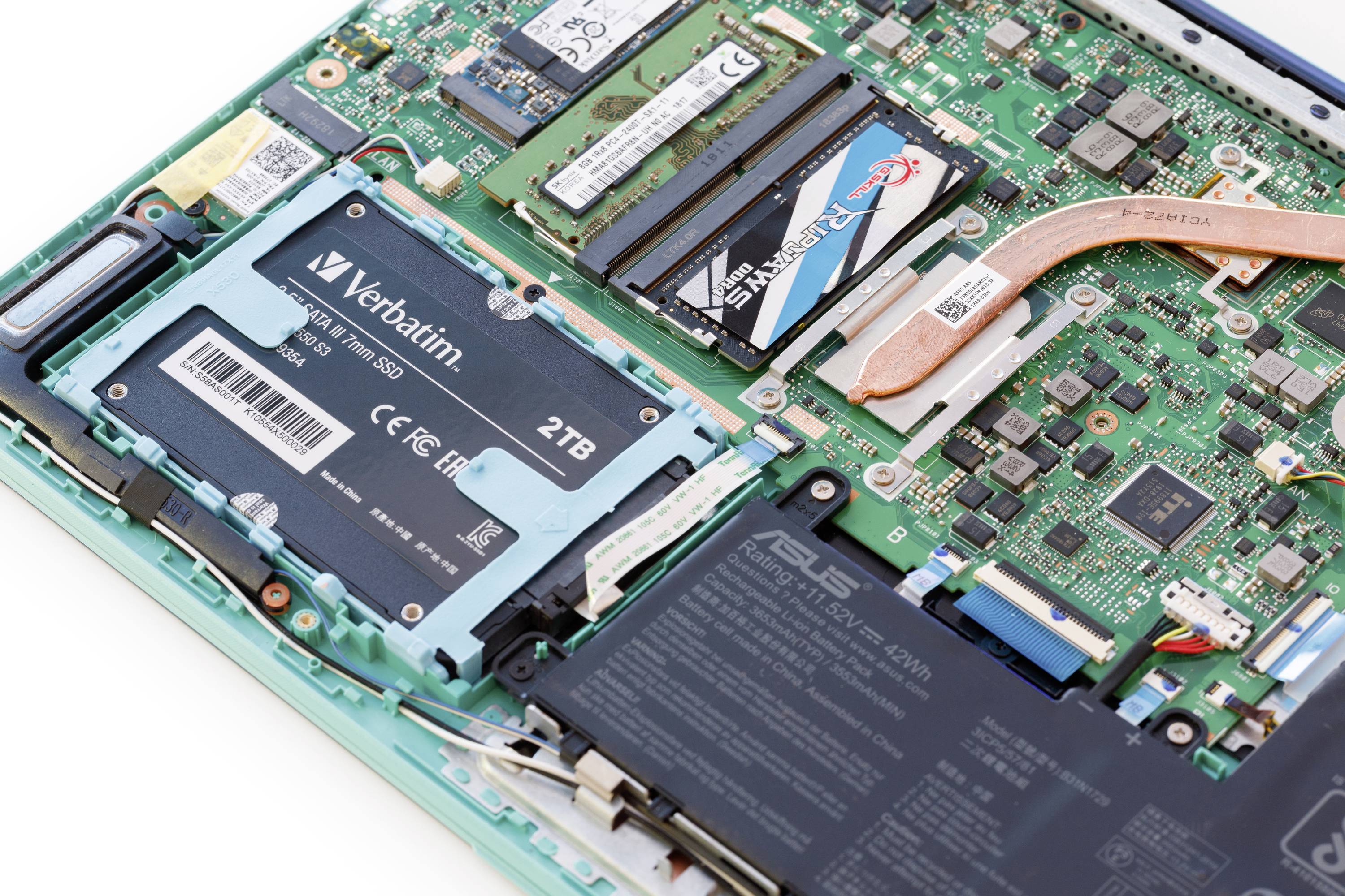 Close-upfoto van een printplaat met een open laptopbinnenkant, toont RAM-modules, een 2-TB-SSD en verschillende elektronische componenten.