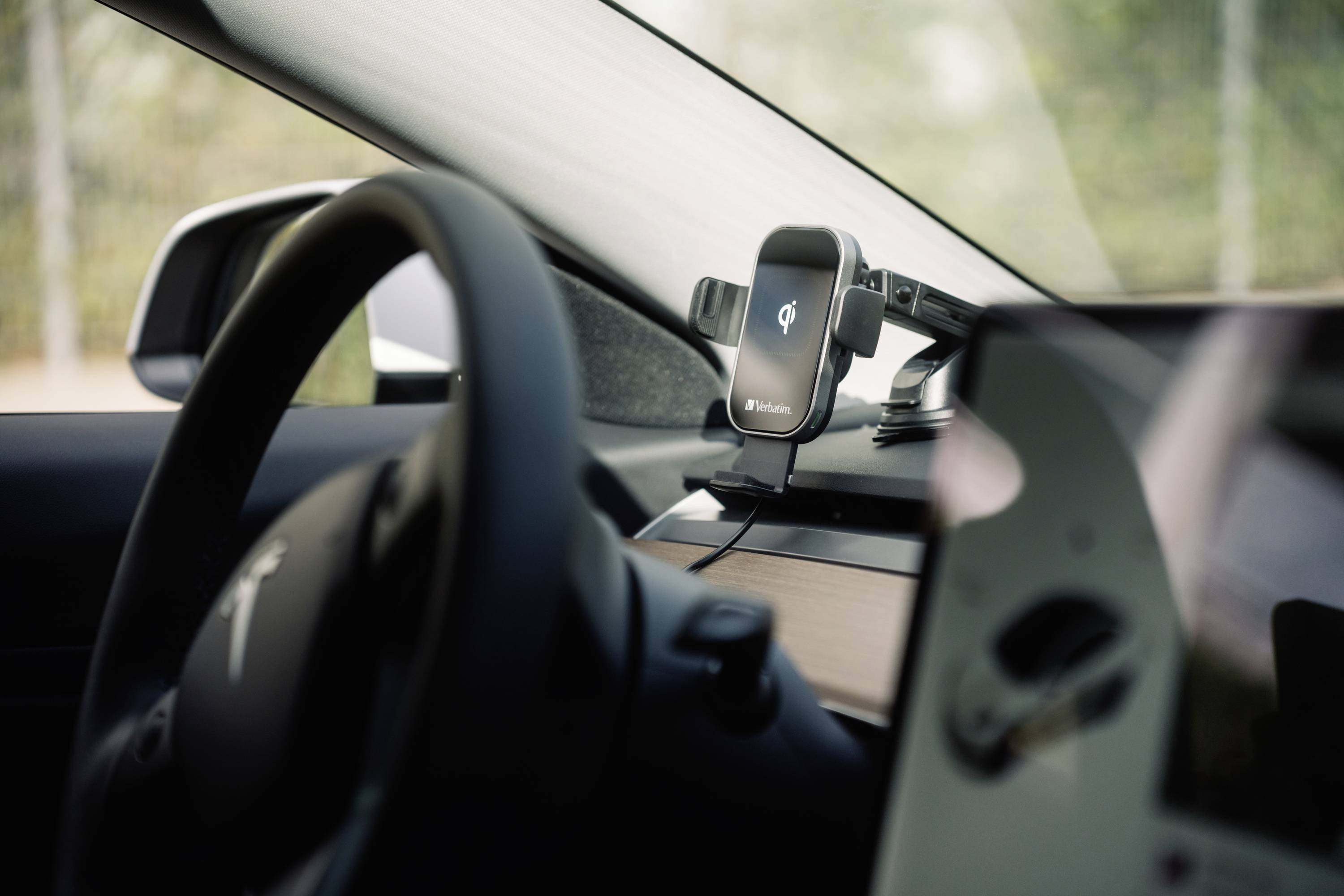 Stuurwiel en telefoonhouder in een moderne auto met centraal scherm, onduidelijke scherminhoud.