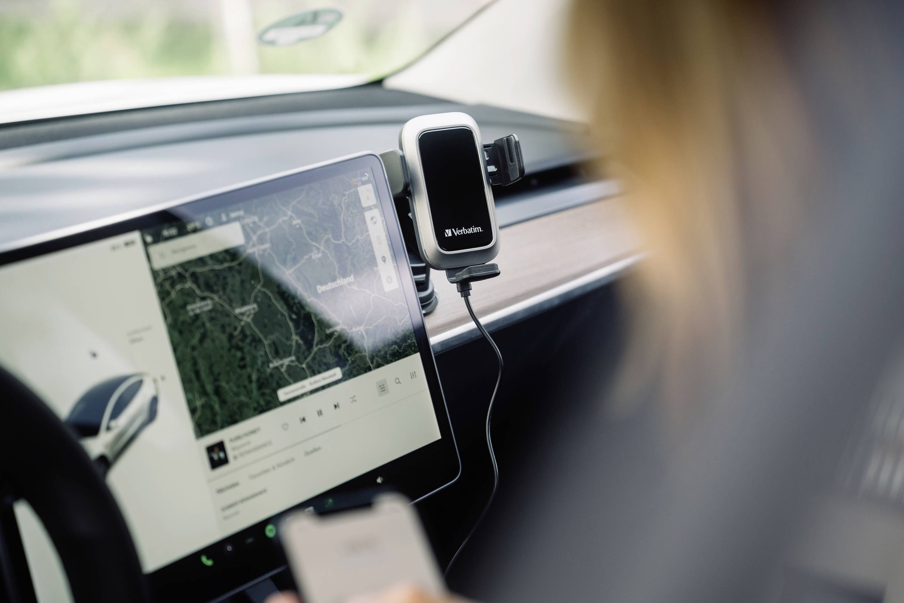 Een persoon in de auto bedient een smartphone. Een GPS-navigatiesysteem op het display toont een kaartweergave.