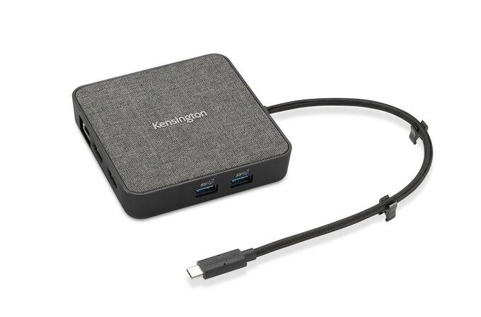 Een vierkante USB-C-hub met stoffen oppervlak en meerdere aansluitingen, waaronder twee USB-A-poorten.
