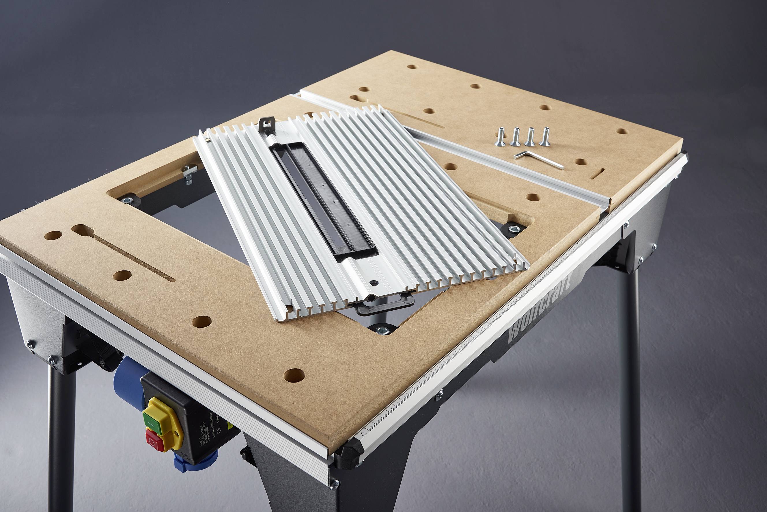 'Een houten werktafel met een afneembaar metalen onderdeel en vier schroeven rechtsboven.'