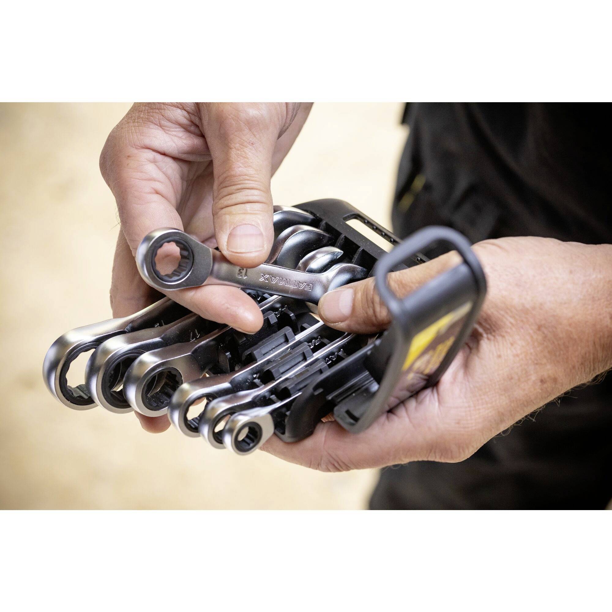 Een persoon houdt een set open ringsleutels in verschillende maten vast, klaar voor gebruik.