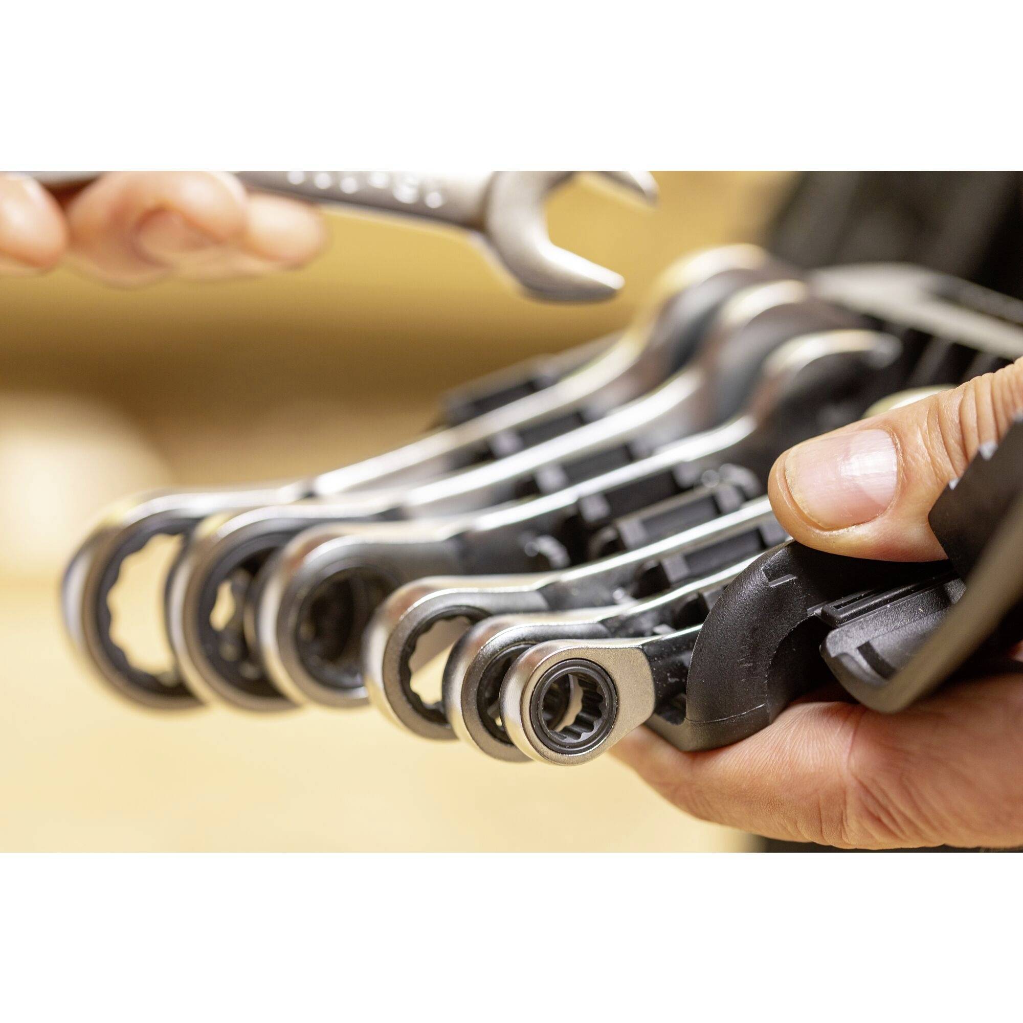 Close-up van handen die een set open moersleutels overdragen, focus op het gereedschap, achtergrond onscherp.