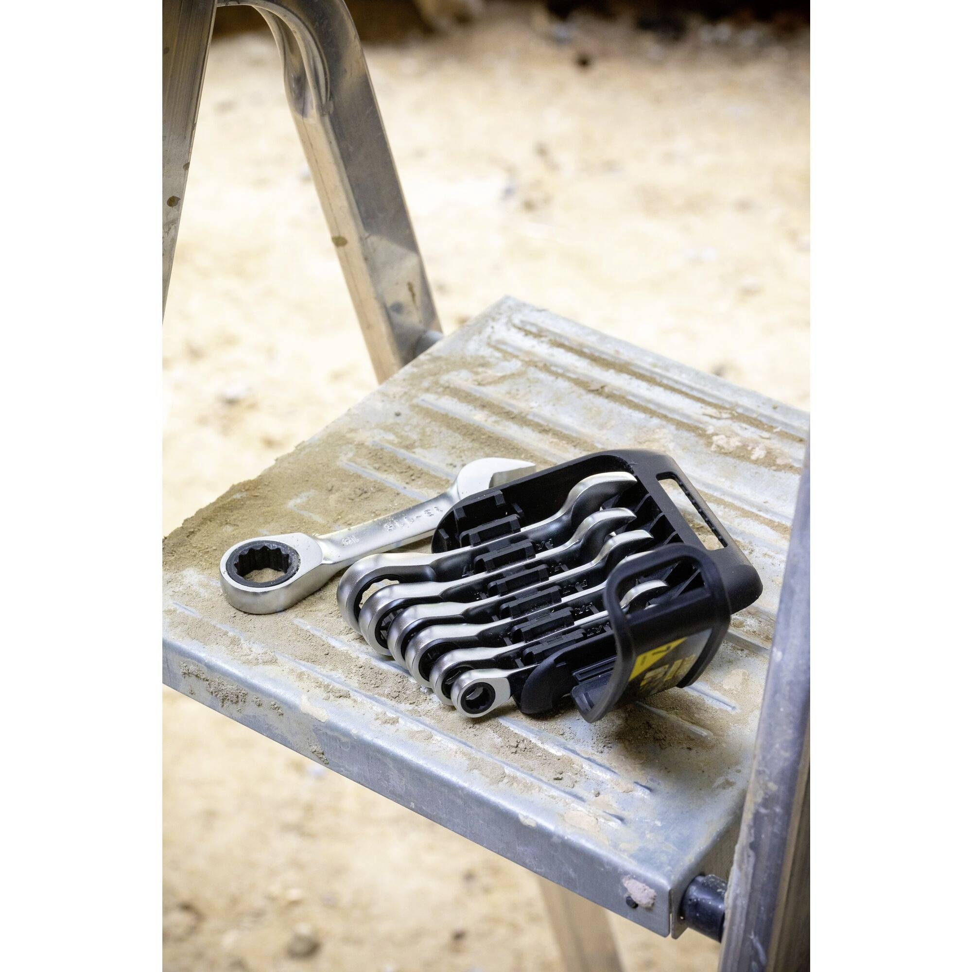 Een set moersleutels in verschillende maten ligt op een ladder, klaar voor gebruik bij reparatie- of montagewerken.