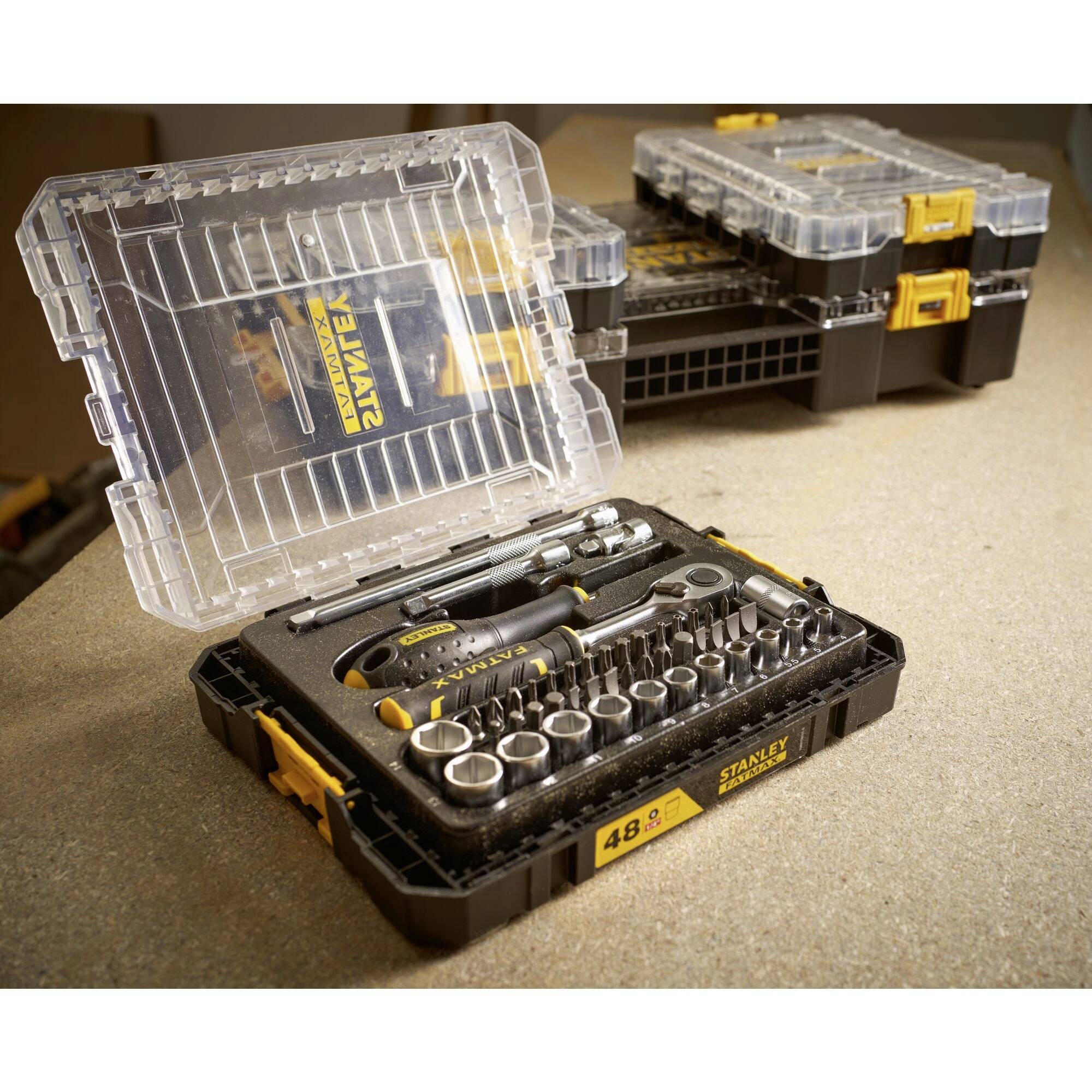 Een open gereedschapsset op een tafel met verschillende dopsleutels en een schroevendraaier. Op de achtergrond twee gesloten koffers.