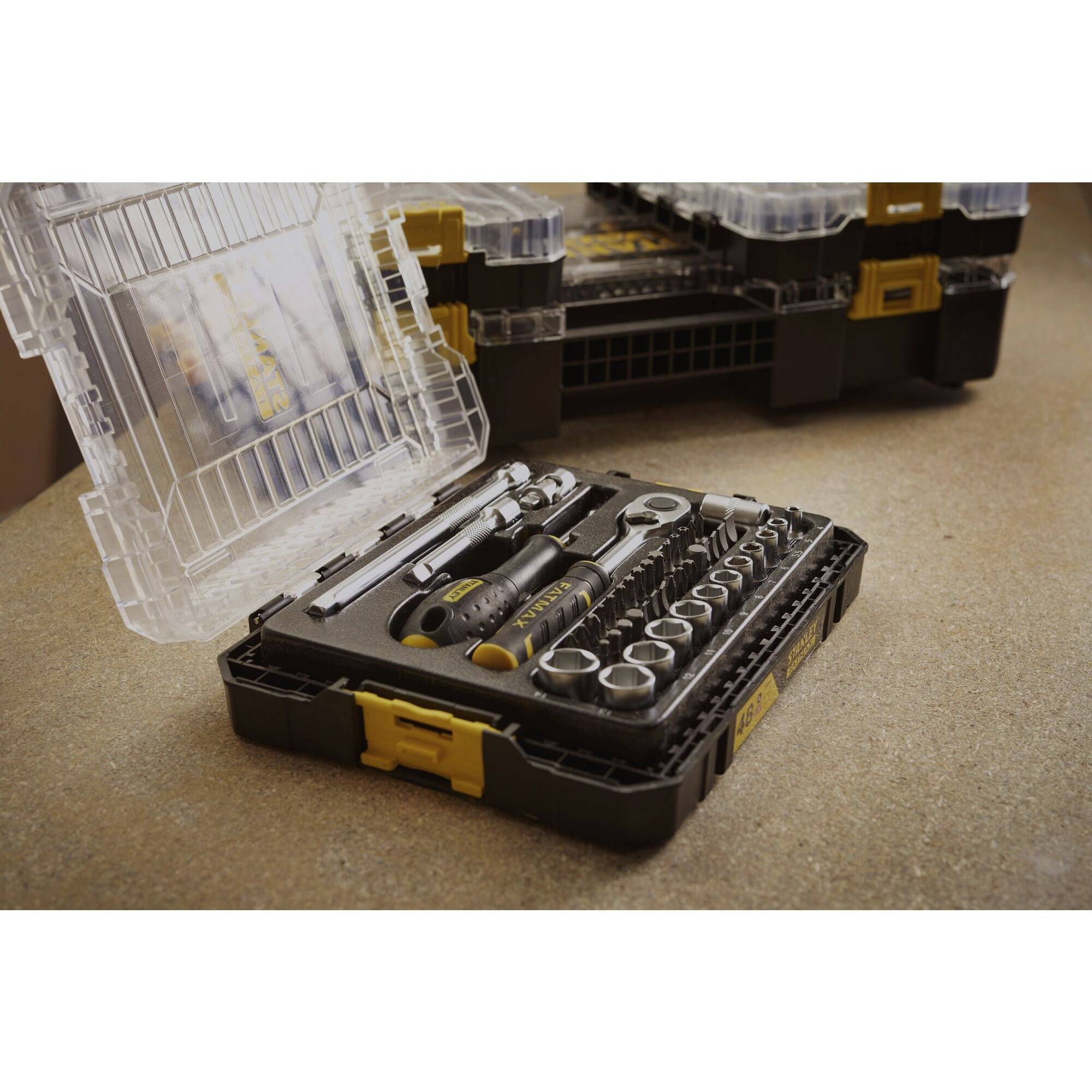 Een geopende gereedschapskoffer met verschillende gereedschappen, waaronder moersleutels en dopsleutels, op een werkbank.