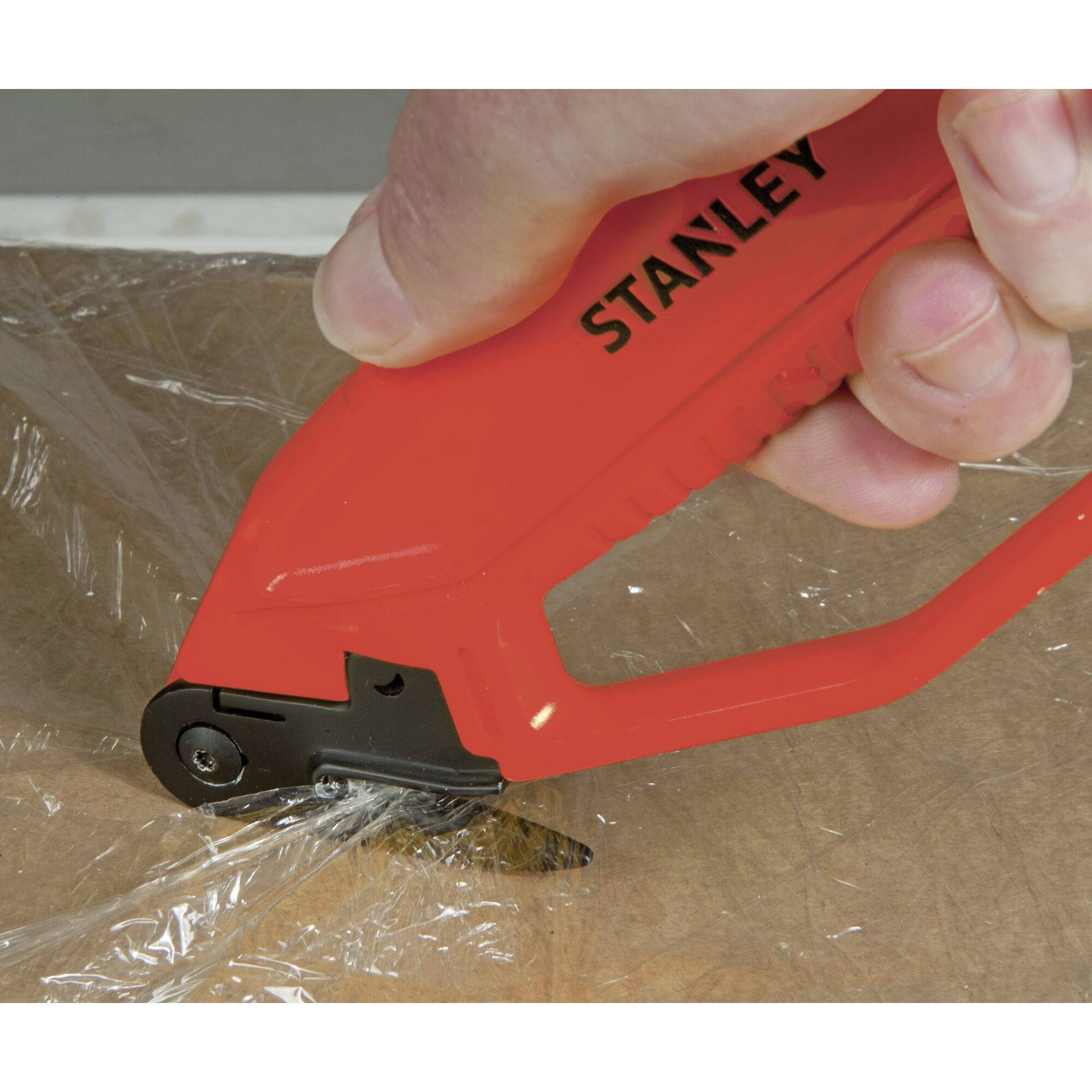 Een rode veiligheidsfolie wordt doorgesneden met een gespecialiseerd gereedschap dat met één hand wordt vastgehouden.