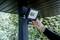Een persoon installeert een LED-schijnwerper met bewegingssensor aan een houten paal onder een afdak buiten.