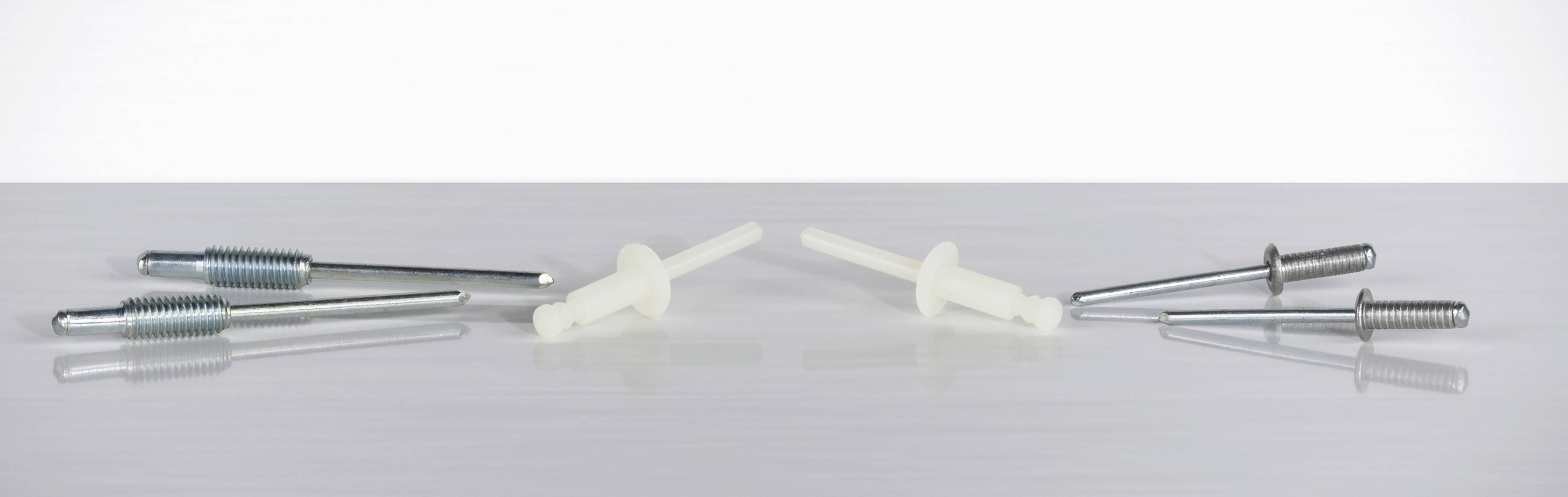 Twee groepen chirurgische schroeven op een grijze ondergrond, links metallic, rechts wit. Dienen medische doeleinden.