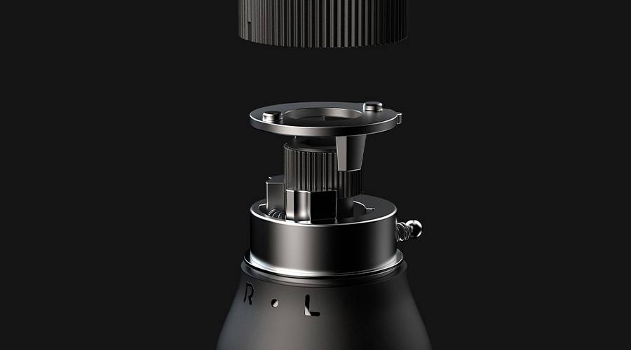 Close-up van een technisch apparaat in onderdelen op een zwarte achtergrond. Toont de bovenste mechanische componenten van een machine.