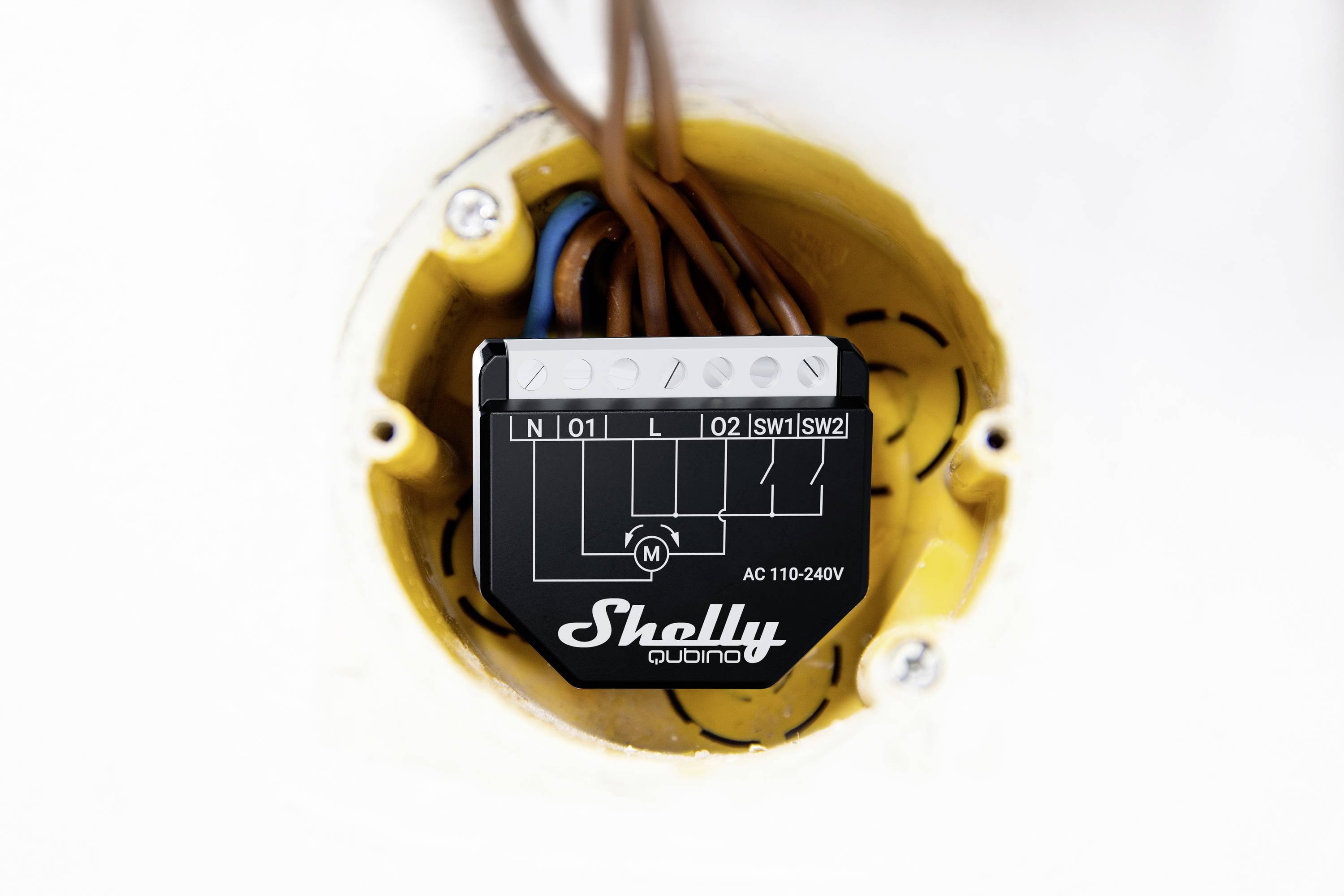 Een zwarte Shelly-schakelactor in een open wanddoos met aangesloten kabels. Geschikt voor 110-240V wisselstroom.
