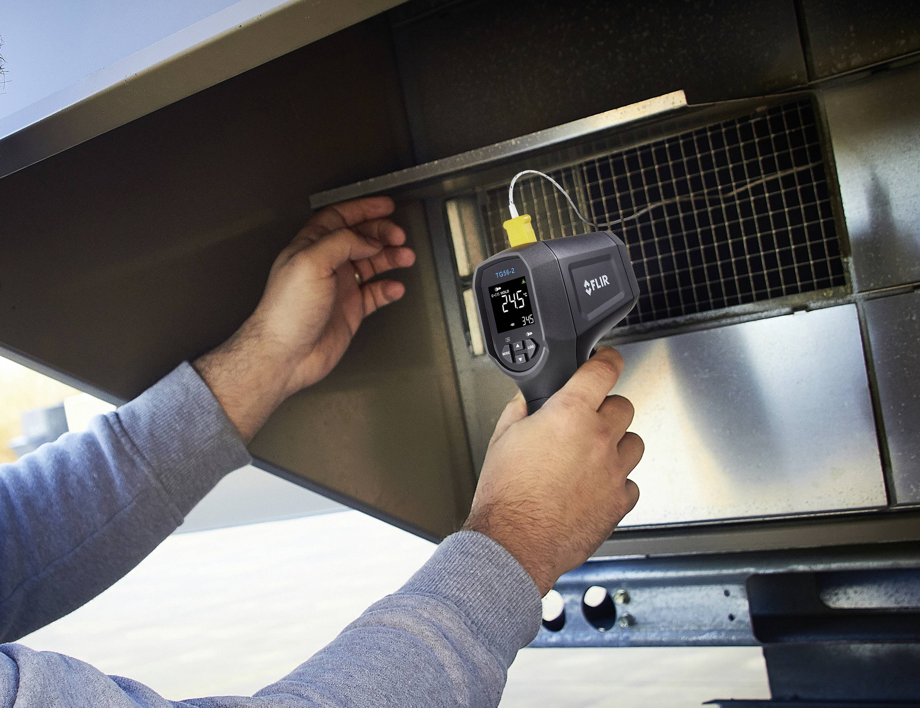 Een persoon meet de temperatuur bij een ventilatierooster met een digitaal thermometer. Het display toont '25,4°C'.