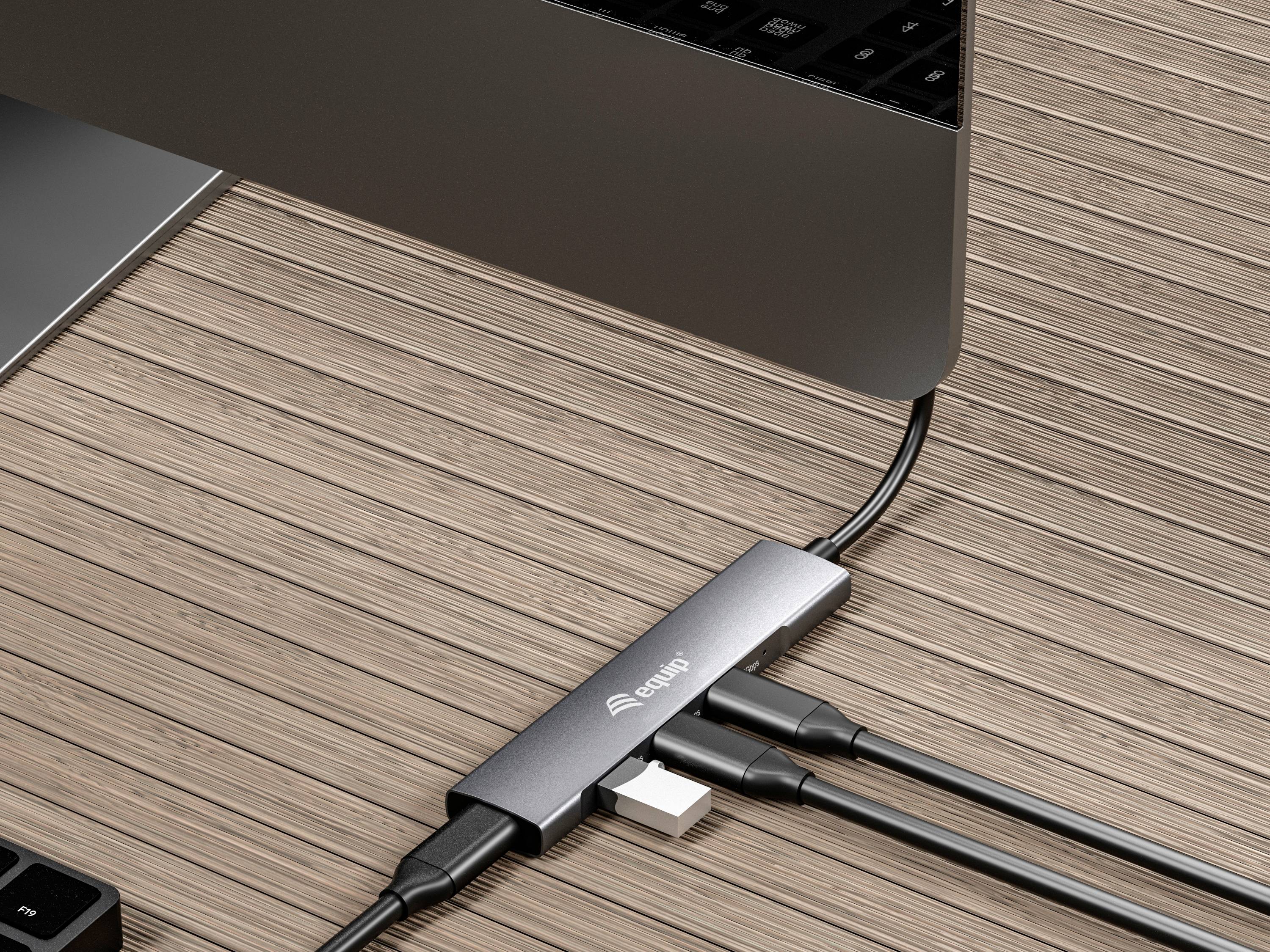 Een laptop staat op een houten tafel, verbonden met een USB-hub die meerdere kabels ontvangt. De focus ligt op de verscheidenheid aan aansluitingen.