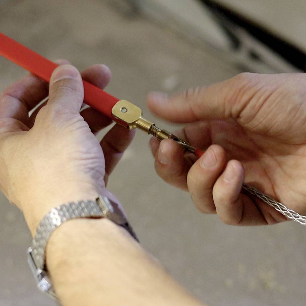 Handen houden een touw vast en draaien het met een gereedschap. Concentratie op handvaardigheid en precisie.