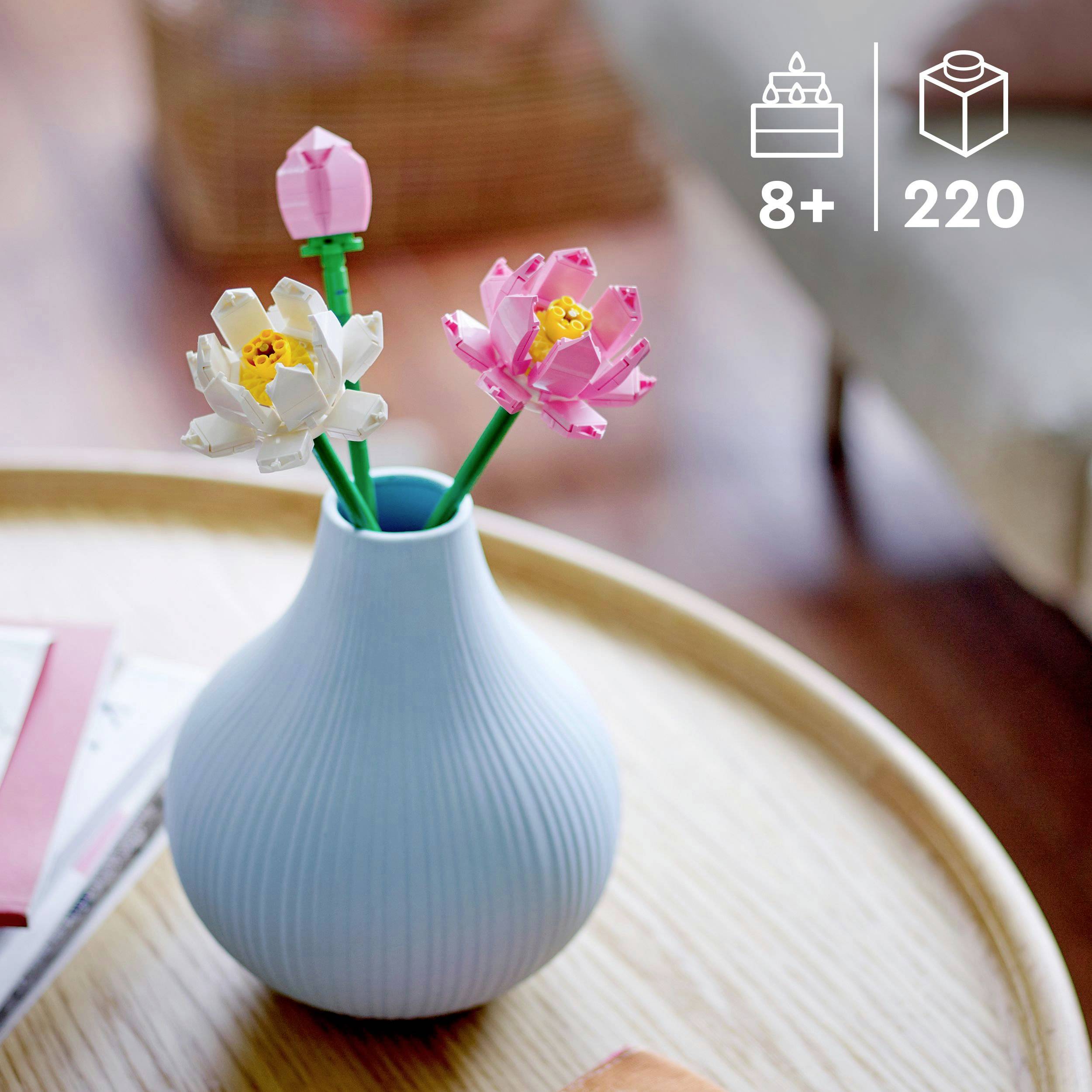 Een ronde houten tafel met een blauwe vaas die kleurrijke LEGO-bloemen bevat. Op de achtergrond onscherpe meubels en decoratie.