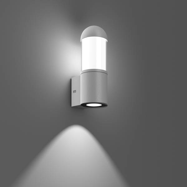 Een moderne, ronde wandlamp van metaal verlicht de grijze muur. Hij straalt neerwaarts gericht licht uit en creëert een elegante sfeer.