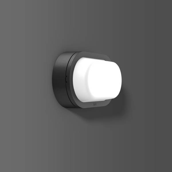 Een witte, rechthoekige bewegingsdetector op een grijze achtergrond, gemonteerd op een zwarte, ronde houder aan de muur.