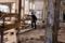 Een bouwvakker in beschermende uitrusting richt een houten steiger op een bouwterrein. Op de achtergrond bevindt zich bouwmateriaal en een gebouw.