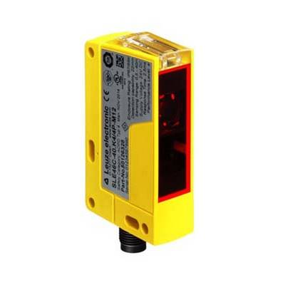 Een gele, rechthoekige sensor met een zwarte aansluiting en een rood venster, gebruikt voor objectdetectie in industriële toepassingen.