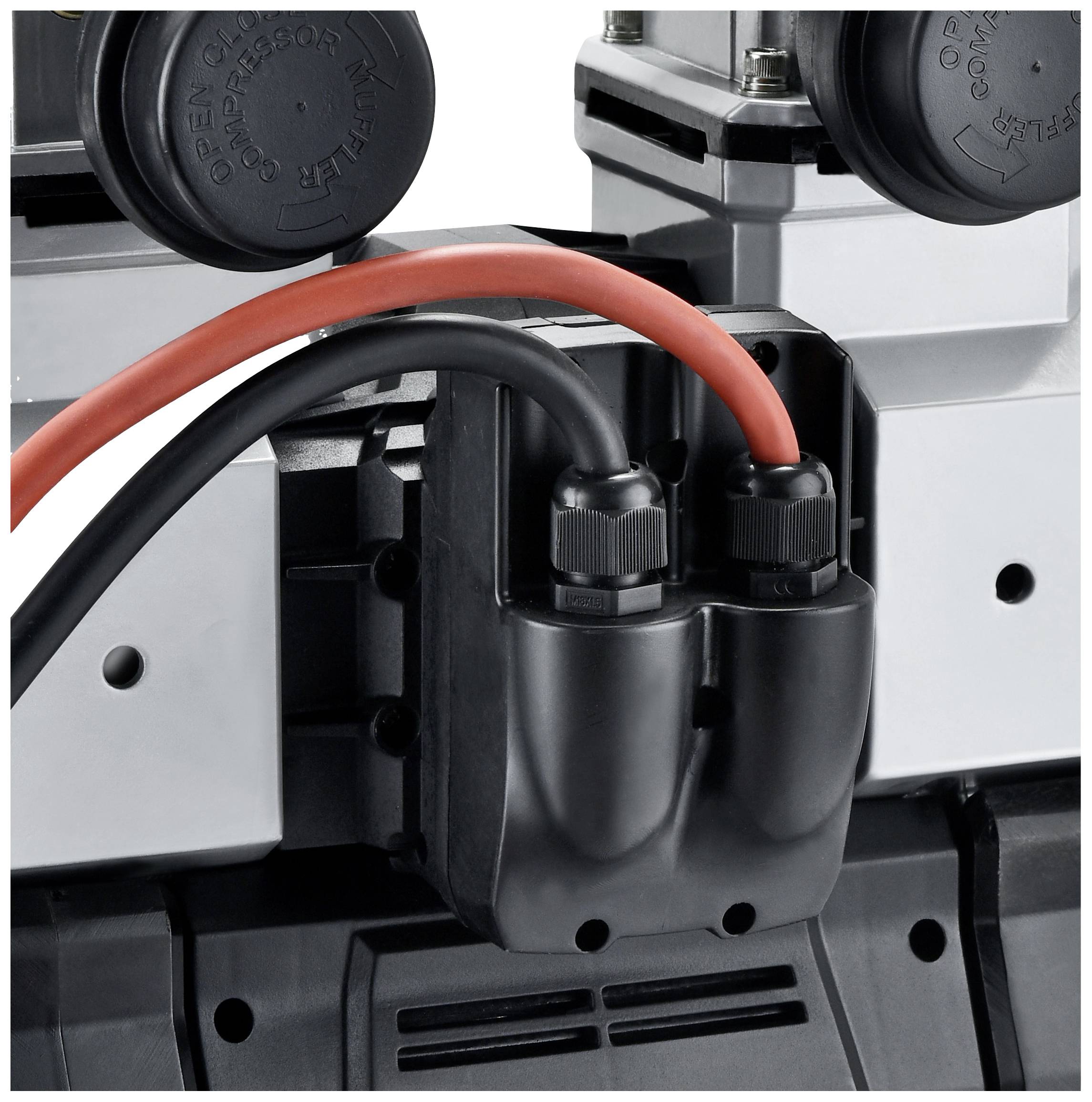 Een zwart elektrisch apparaat met twee rode en zwarte kabels die in aansluitingen zijn gestoken. Het apparaat lijkt deel uit te maken van een grotere machine-installatie.