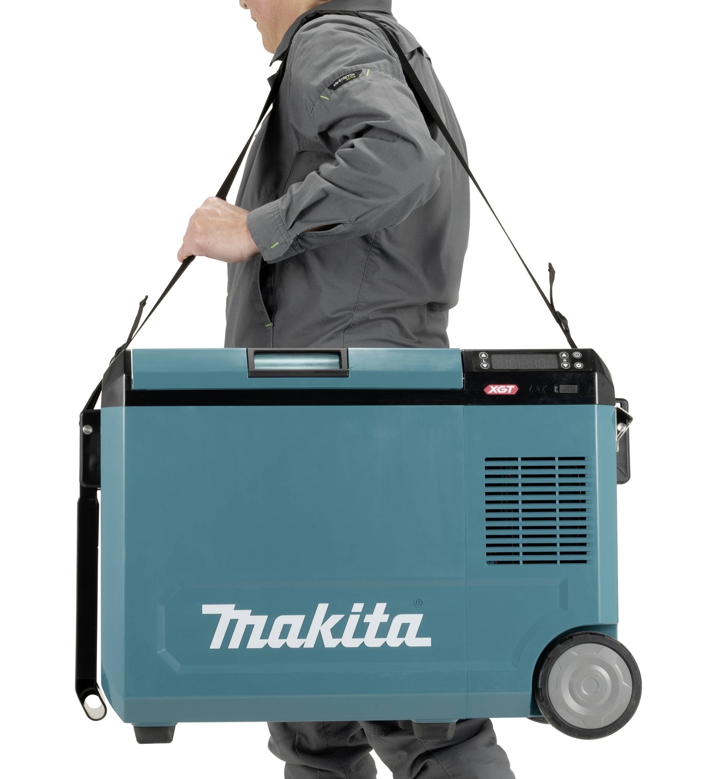 Een persoon draagt een draagbare koelbox van het merk Makita met een schouderband. De koelbox heeft wielen en is in een blauw-groene tint.