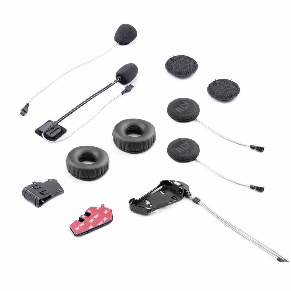 Een motorrijders-communicatieset, bestaande uit microfoons, oordopjes, montagekits en kabels, gerangschikt op een witte achtergrond.