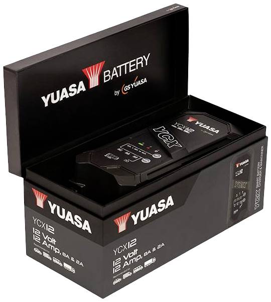 Een zwart Yuasa-accuoplader YCX12 in een geopende verpakking, toont de voorkant met 12 volt en 12 ampère specificaties.