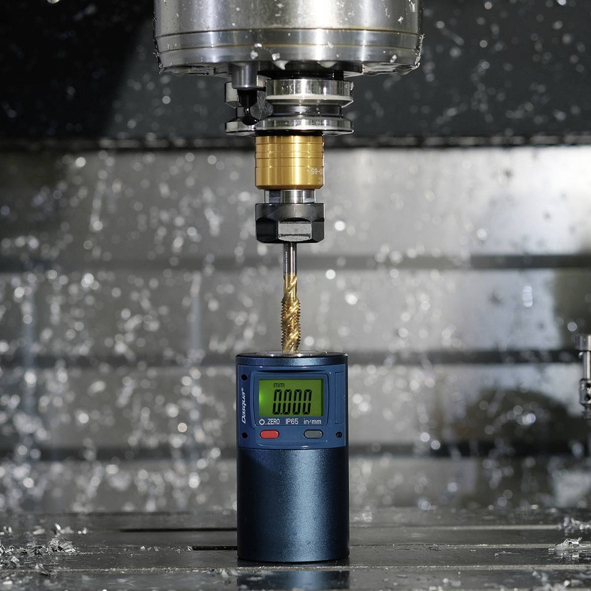 Een freesmachine bewerkt nauwkeurig een metalen onderdeel, terwijl spaanders om de machine heen vliegen. Een meetinstrument toont het toerental aan.